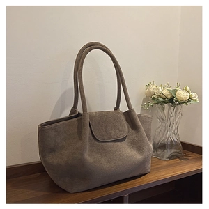 Detalle del bolso tote de ante en estante de madera con decoración floral de hogar