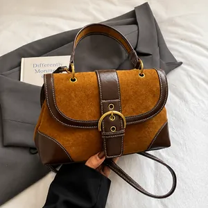 Detail of vintage saddle bag featuring caramel suede texture and large metal buckle