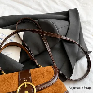 Detail showing the adjustable leather strap and vintage gold metal buckle on a suede bag