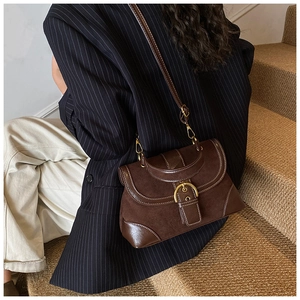 Detail of vintage dark brown saddle bag with gold buckle and adjustable strap on a model