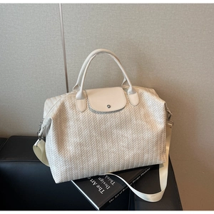 Détail du sac de voyage crème à texture tissée avec bandoulière et boucles