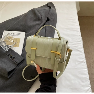 Detail van mintgroene mini-tas van rimpelleer met goudkleurige hardware en greep
