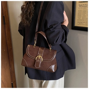 Macro detail of a vintage brown saddle bag with gold buckle and contrast stitching