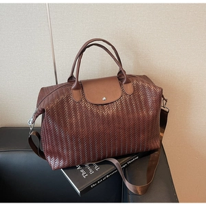 Vue détaillée de la texture à chevrons marron foncé et du rabat en cuir du grand sac