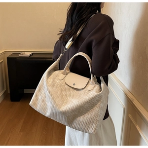 Détail du sac cabas tissé crème montrant la texture, le rabat en cuir et les poignées