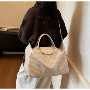Détail du grand sac cabas tissé blanc cassé avec poignées en cuir porté par un mannequin