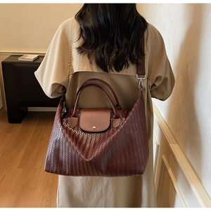 Sac cabas tissé marron avec rabat en cuir porté par un mannequin dans une pièce