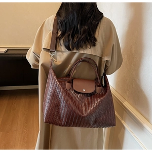 Détail d'un sac à main marron foncé à texture tissée avec rabat et bandoulière réglable