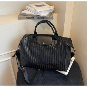 Détail de la texture tissée à chevrons noirs du grand sac de voyage avec rabat