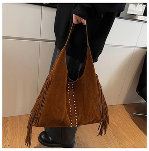 Dettaglio della borsa tote in pelle scamosciata marrone con borchie e frange