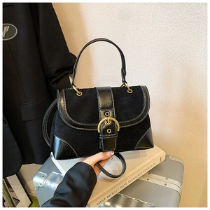 Detail of vintage black saddle bag with matte leather panels and gold buckle