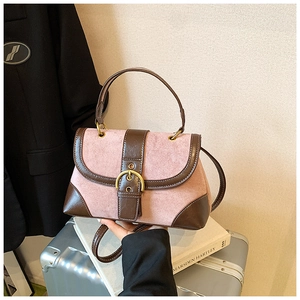 Detail of pink suede and brown leather saddle bag with golden circular buckle clasp