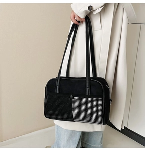 Detailweergave van de zwarte schoudertas met strass en zilveren studs op model
