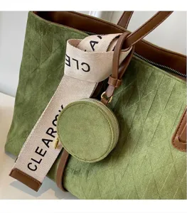 Close-up of green suede tote bag with diamond pattern and brown leather straps