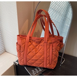 Vue macro d'un sac cabas en nylon matelassé orange avec des coutures en losanges