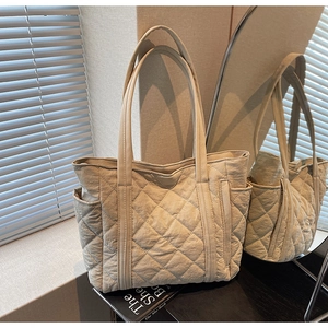 Détails du motif matelassé en losange et poche latérale du sac fourre-tout crème