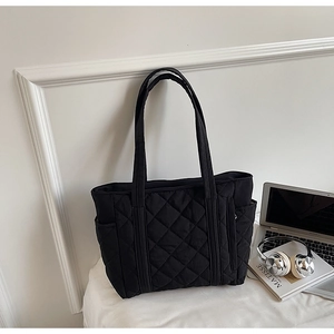 Détail du sac cabas matelassé noir montrant sa grande capacité, sa poche et sa texture douce