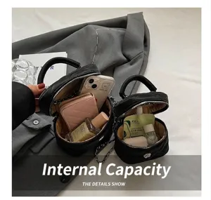 Vista interior del bolso acolchado negro mostrando espacio para perfume y móvil