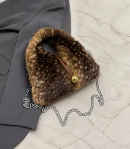 Détail d'un sac à main en fausse fourrure léopard avec fermoir boule dorée et chaîne