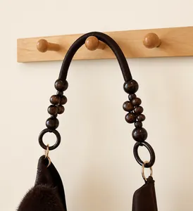 Detail of braided coffee-colored handles with decorative wooden beads on a brown tote bag