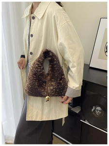 Détail d'un sac à main en peluche imprimé animal avec chaîne et breloque boule dorée