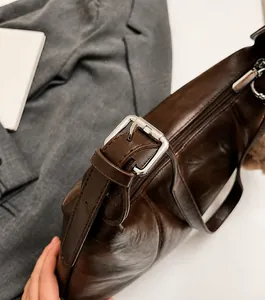 Dettaglio di una borsa in pelle marrone retrò con finitura lucida e fibbia in metallo