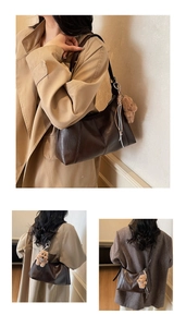 Dettaglio borsa hobo in pelle marrone scuro con cuciture e ciondolo a forma di orsetto