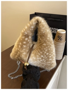 Détail du sac triangulaire en peluche léopard avec une breloque boule en métal doré