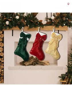 Detail showing red green and gold sequined Christmas stockings with bows on a fireplace