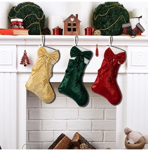Close-up of three festive sequined Christmas stockings with bows hanging on a fireplace