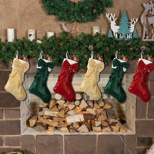 Set of 6 sequined Christmas stockings in red, green and gold hung on a fireplace