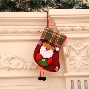 Red Christmas stocking with plaid cuff and 3D Santa Claus hanging on fireplace mantel