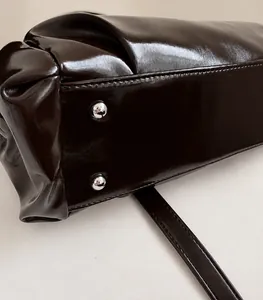 Macro view of dark brown polished leather bag bottom with silver metal protective studs