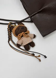 Détail d'un pendentif ours en peluche marron avec t-shirt rayé sur un sac en cuir