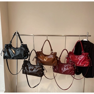 Row of large faux leather bags showing glossy finish, pleated sides and diverse colors