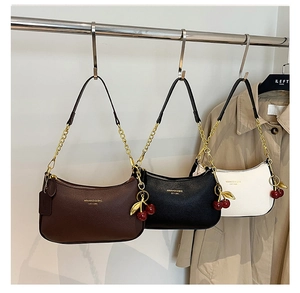 Gros plan de sacs sous les bras en cuir grainé avec pendentifs cerise et chaînes