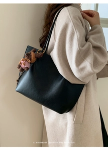 Détail du sac cabas en cuir grainé noir avec pendentif ours en tricot et fine bandoulière