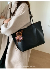 Détail d'un sac cabas en cuir noir avec un pendentif d'ours en peluche marron mignon
