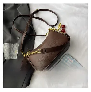 Sac bandoulière marron grainé avec chaîne dorée et petit pendentif cerise