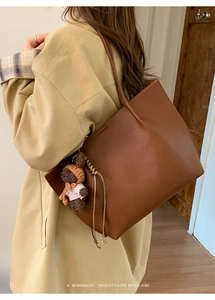 Grand sac cabas en cuir marron foncé avec pendentif ours porté à l'épaule par le mannequin