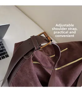 Detail view of adjustable leather strap with bronze buckle on coffee suede tote bag