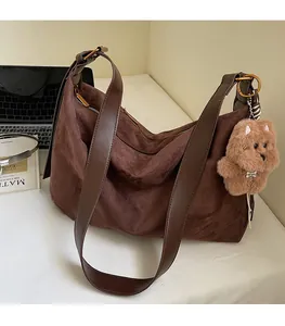 Detail of dark brown suede hobo bag with leather shoulder strap and plush dog charm