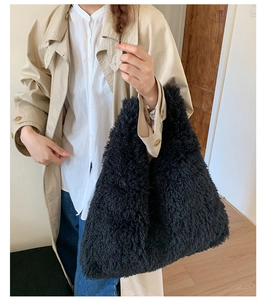 Detalle de bolso tote grande negro de borreguillo llevado por una modelo en interiores