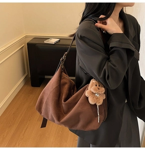 Brown faux suede hobo bag with teddy bear charm shown in a lifestyle setting