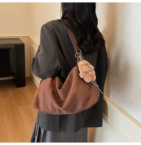 Detailed view of brown suede hobo bag with a cute plush bear charm for autumn style