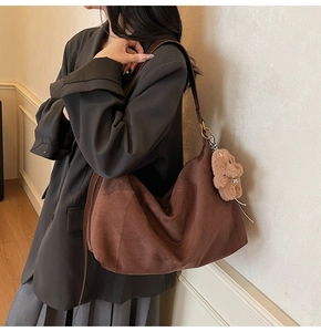 Brown suede hobo bag with moon-shaped pleats and plush charm shown on model