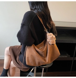 Detail of dark brown suede tote bag with silver zipper and cute plush bear charm