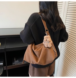 Detail of dark brown faux suede hobo bag with a cute plush bear charm on a female model