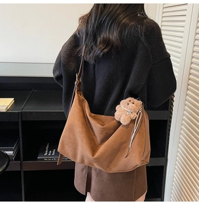Detailed view of brown suede hobo bag with wide strap and cute teddy bear charm