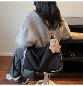 Large black suede hobo bag shown on a model with a cute bear charm and pearl detail